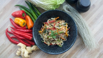 Flatlay of japchae, chilli and peppers.
