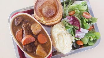 A plate of stew with mash potatoes and salad. 