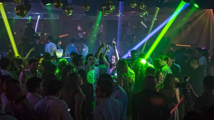 Party goers dancing amidst green lights at Zouk
