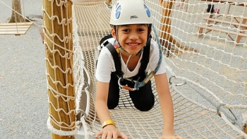 Smiling child enjoying the Forest Adventure obstacle course