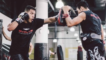 Two men practicing Muay Thai with punching pads