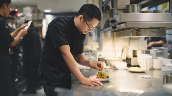 Michelin-starred Peranakan Chef Malcolm Lee working on a dish in Candlenut Kitchen