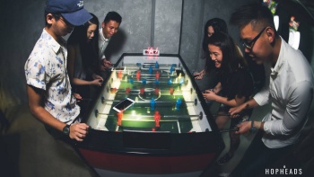 A group of friends engaged in a foosball game