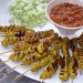 A plate of satay with chilli and raw onions