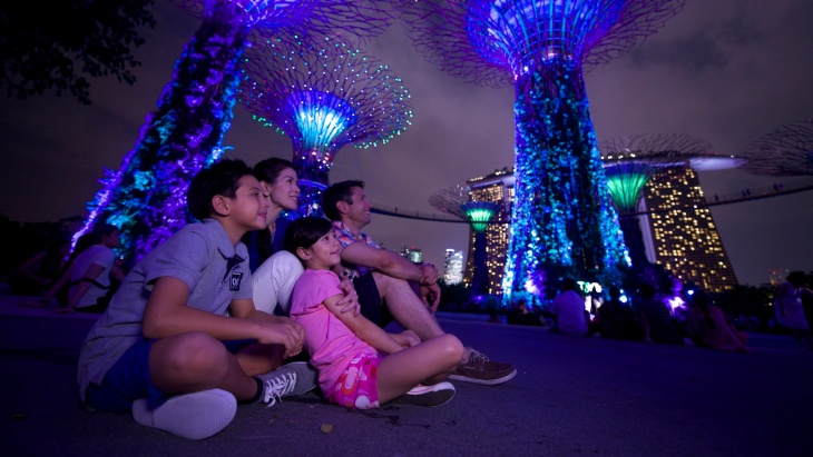 A family entertained by the colourful lights from the Supertrees at night