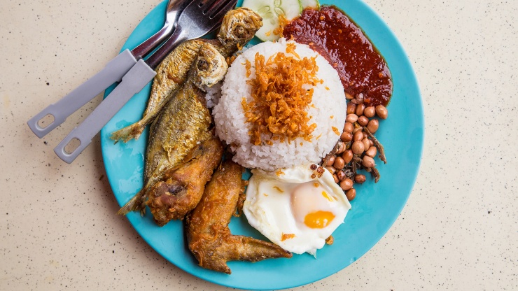 Sepiring nasi lemak dengan ikan goreng, mentimun, kacang, telur, dan sambal.