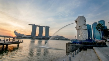An evening side view of the Merlion spouting water into the river