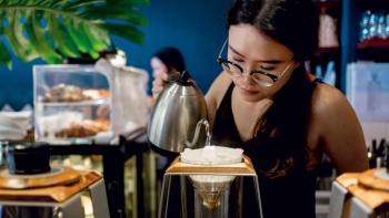 Barista menuangkan ke dalam penyeduh kopi di Atlas Coffeehouse