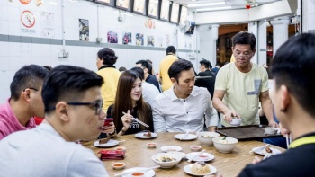 Pria menyajikan makanan kepada sekelompok pengunjung di Swee Choon Tim Sum