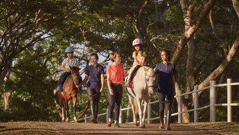 Ibu mendampingi anak-anaknya menunggang kuda poni di Gallop Stable