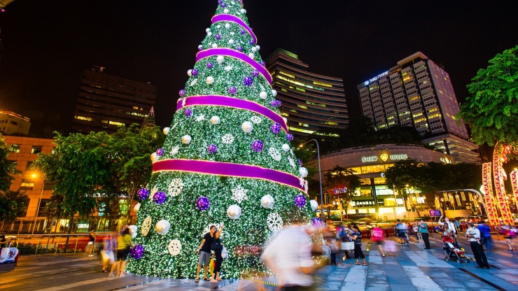 Pohon Natal terang dengan gedung Shaw House di latar belakang.