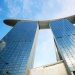 Foto fasad Marina Bay Sands<sup>®</sup> nan cantik diambil dari bawah mengarah ke langit biru nan menawan 