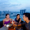 Foto kelompok yang terdiri dari tiga orang teman sedang menikmati kuliner, bersantap ditemani panorama langit di atas LeVeL33