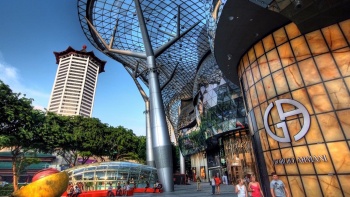 Foto tampilan lebar eksterior ION Orchard, dengan Tang di latar belakang.