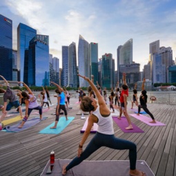Sekelompok orang melakukan yoga berlatar cakrawala Singapura
