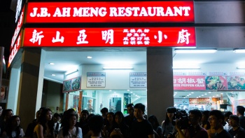 Sekelompok orang berdiri di depan JB Ah Meng, restoran zi char di Geylang Lorong 30.