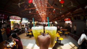 Foto sudut pandang minuman sari tebu dengan pemandangan Maxwell Food Centre dan sekitarnya