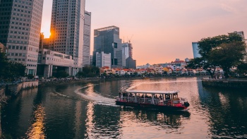 Foto kapal pesiar pelayaran sungai saat senja di Singapore River 