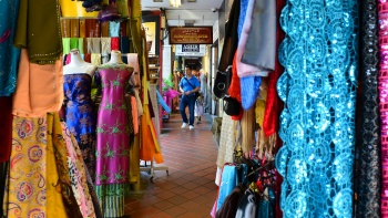 Pemandangan koridor yang penuh dengan pajangan bahan kain di luar toko yang memenuhi Kampong Gelam