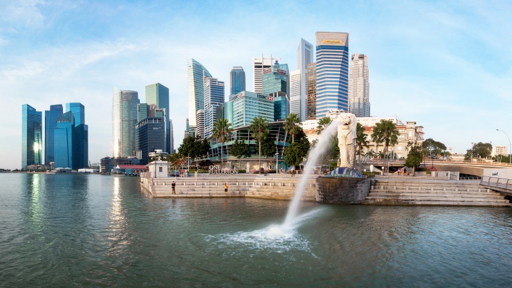 シンガポールの街のスカイラインを背に立つマーライオン
