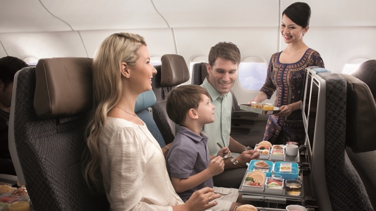 シンガポール航空の機内で、3人家族の乗客にサービスを提供するSQガール