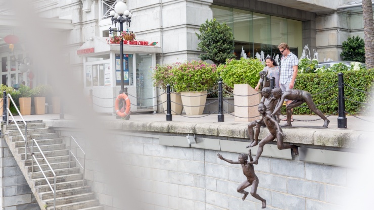 「川辺の人々」の彫像を見ている観光客