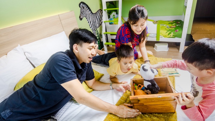 디’리조트의 레인포레스트 패밀리 정글 룸에서 두 아이와 놀이를 하고 있는 부모 