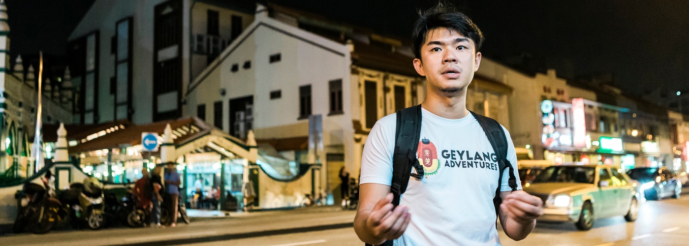 Cai Yinzhou introduces the night life of Geylang to a tour group. 