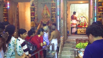 A group of worshippers standing and waiting outside the temple.