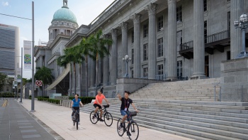 A couple cycling with a tour guide in front of National Gallery Singapore