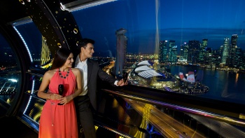 A couple viewing the Singapore skyline in the evening from a Singapore Flyer cabin