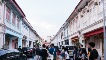 A group of students walking across a row of shophouses