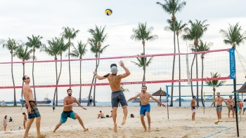 A group of players engaging in a beach volleyball game in Sentosa.