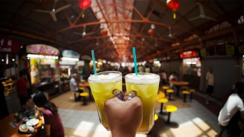 Point of view shot of sugar cane drink with a wide view of Maxwell Food Centre