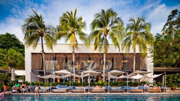 Beautiful Swimming pool and blue sky with a row of deck chairs and coconut palm trees at Tanjong Beach Club Sentosa