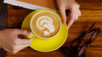 มุมมองจากด้านบนลงล่างของกาแฟหนึ่งถ้วยในแบบศิลปะลาเต้ที่สวยงาม