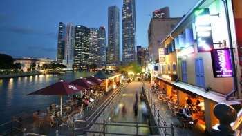 ทิวทัศน์ยามค่ำของย่าน Boat Quay (ท่าเรือโบ๊ทคีย์) ที่มีผู้คนคึกคักและมีภาพเส้นขอบฟ้าเป็นฉากหลัง