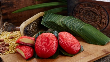 ขนมอังกู กูเอห์ (ขนมเต่าแดง) สองชิ้น และอีกชิ้นที่ผ่าครึ่งเผยให้เห็นไส้ข้างใน