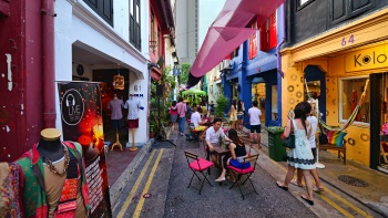 ผู้มารับประทานอาหารที่นั่งอยู่ในบริเวณกลางแจ้งย่าน Haji Lane ที่เต็มไปด้วยตึกแถวสีสันสดใส