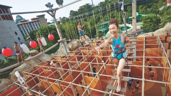 หญิงสาวในชุดว่ายน้ำกำลังปีนเขาใน Wet Maze ของสวนน้ำแอดเวนเจอร์ โคฟ 