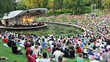 ผู้คนกำลังชมการแสดงที่ Shaw Foundation Symphony Stage (เวทีการแสดงดนตรีซิมโฟนี่ของมูลนิธิชอว์) ณ Singapore Botanic Gardens (สวนพฤกษศาสตร์สิงคโปร์) 