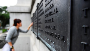 ผู้มาเยี่ยมชมกำลังดูรายชื่อที่สลักไว้บนแผ่นหินใน Cenotaph อนุสรณ์สถานสงครามแห่งนี้
