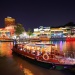 เรือบัมโบ๊ทที่จอดเลียบแม่น้ำสิงคโปร์ในยามค่ำคืน และมีป้าย Clarke Quay ปรากฏเป็นฉากหลัง