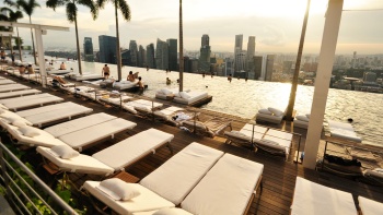 วิวจากสระว่ายน้ำลอยฟ้าของ Marina Bay Sands<sup>®</sup> SkyPark ที่มองออกไปเห็นเส้นขอบฟ้าของสิงคโปร์ในยามบ่าย