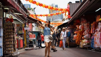 นักท่องเที่ยวในย่าน Chinatown สิงคโปร์กำลังถ่ายเซลฟี่กับโคมจีนและให้ด้านหน้าร้านขายของเป็นแบ็คกราวด์