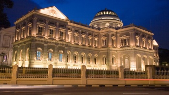 ถ่ายภาพโดย คณะกรรมการมรดกทางวัฒนธรรมแห่งชาติ ด้านหน้าของ National Museum of Singapore ในยามค่ำคืนที่สว่างไสวด้วยแสงไฟ