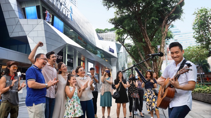 ครอบครัวกำลังชมการเล่นดนตรีริมถนน Orchard Road