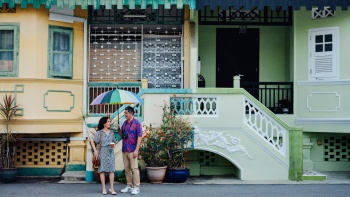 คู่รักวัยกลางคนยืนอยู่หน้าตึกแถวสีสันสดใสในย่าน JooChiat Katong