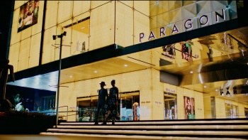 ภาพเงาของคู่รักที่เดินลงบันไดนอกห้าง Paragon ในยามค่ำคืน 