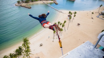 หญิงสาวกระโดดจาก AJ Hackett ที่ระดับความสูงปานกลางของเกาะ Sentosa และมองเห็นวิว Siloso Beach (ชายหาดซิโลโซ)